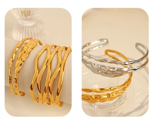 Detail of layered gold and silver stainless steel bangles with hammered wavy texture