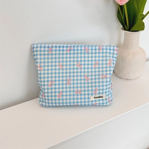 Detail of blue checkered floral makeup bag with pink bow pattern and brand label
