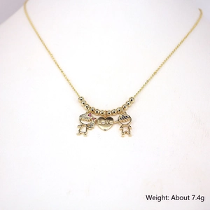 Detail of gold necklace with boy, girl and Love heart pendants featuring micro-set zircons