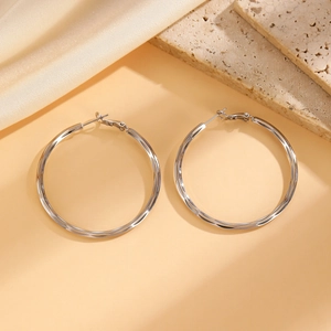 Detailed macro view of large silver hoop earrings featuring a high-polish metallic finish