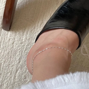 Close-up of minimalist S925 sterling silver chain anklet on female ankle