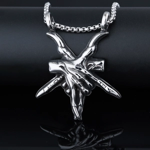 Macro detail of silver gothic demon finger pendant with pentagram on black background