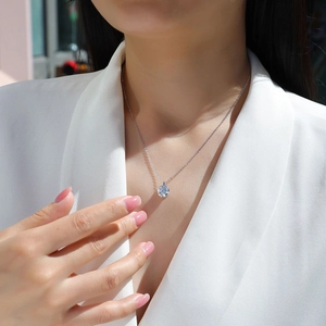 Close-up of a s925 silver moissanite pendant necklace worn on a female neck with white suit