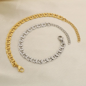 Detailed macro view of 18K gold and silver paperclip link bracelets on fabric