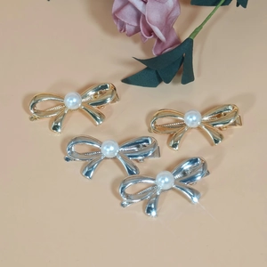 Close-up of four elegant metal bow hair clips with pearls in gold and silver finish