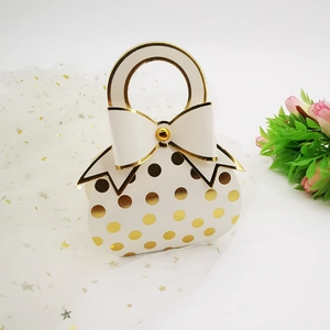 Elegant white wedding favor box with gold foil polka dots and a decorative bow handle