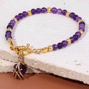 Close-up of purple stone bead bracelet with gold heart pendant and toggle clasp