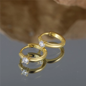 Macro shot of 925 silver golden huggie hoop earring with clear gemstone and S925 hallmark