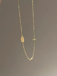 Détail du collier religieux doré avec croix et médaillon Vierge Marie sur chaîne à billes