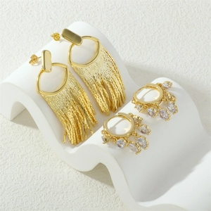 Industrial style gold tassel earrings and zircon hoop jewelry on white wave stand