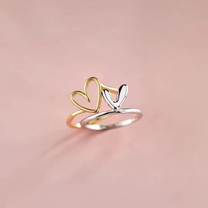 Macro shot of two-tone heart stackable rings in gold and silver on pink backdrop