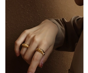 Macro detail of gold croissant ring featuring vintage twisted texture on model hand