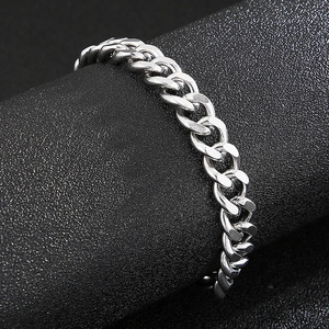 Vue macro d'un bracelet gourmette en argent poli sur un support d'exposition noir