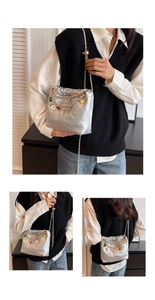 Detail of silver quilted bucket bag with colorful charms and metal chain strap