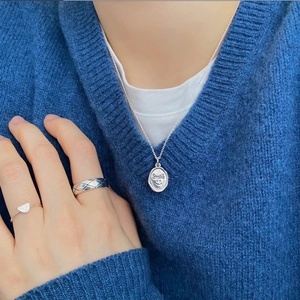 Sterling silver smile face pendant necklace and bear ring set on a blue sweater