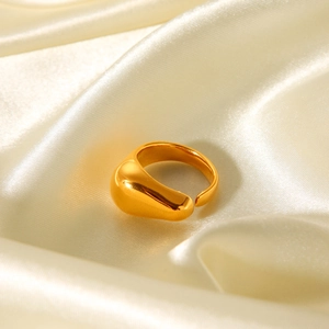 Macro shot of gold teardrop ring featuring high-polish finish on champagne silk