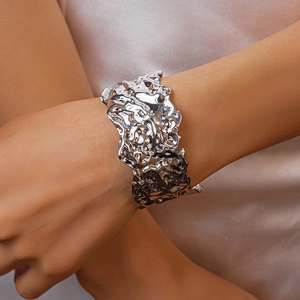 Close-up of a silver liquid metal texture cuff bracelet with a wide open design on wrist