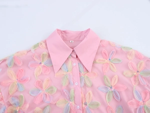Close-up of pink puff sleeve shirt featuring 3D floral embroidery and sequin details