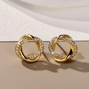 Macro shot of gold knot earrings featuring interwoven bands and micro-set zircon stones