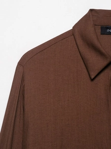 Close-up of a brown linen shirt collar showing fine fabric texture and stitching details