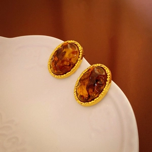 Macro detail of vintage amber resin earrings with textured gold scalloped metal edges