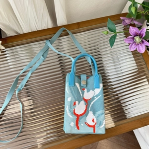 Detail of light blue knitted animal bag with bird pattern and magnetic clasp