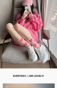Close-up of pink crew socks with red hearts paired with stylish white chunky sneakers