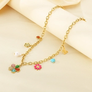 Detailed shot of gold stainless steel necklace with resin flowers and charms on fabric
