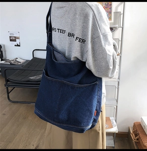 Detail of a large dark blue denim tote bag with front pocket and durable texture