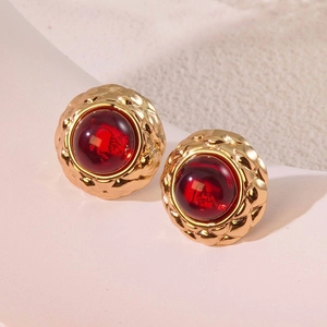 Macro shot of vintage gold stud earrings with red cat eye stone and textured rim
