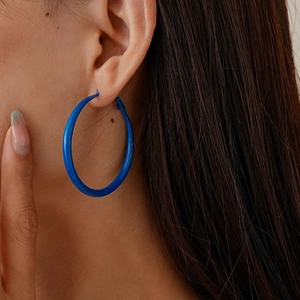 Close-up of a large royal blue geometric hoop earring worn by a model for a chic retro look