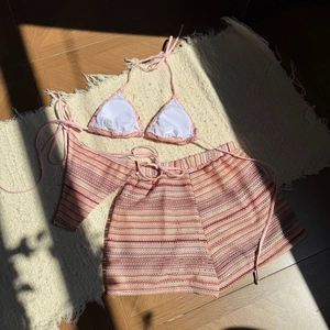 Detail eines rosa Häkel-Bikini-Dreiteilers mit gestreiften Shorts und Ärmeln