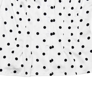 Detailed macro view of white silk fabric with black polka dots and white buttons