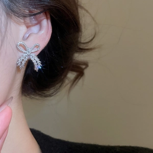 Close-up of sparkling bow-shaped earrings in silver finish with shimmering pavé diamonds