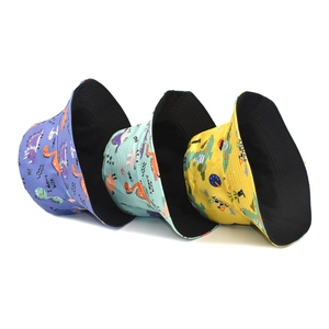 Three colorful reversible bucket hats with dinosaur prints in purple, green and yellow colors