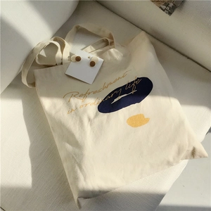 Detailed view of canvas tote bag with artistic color blocks and wood grain earrings