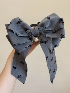 Dettaglio molletta per capelli in tessuto grigio con stampa floreale e perla elegante