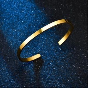 Macro detail of minimalist gold stainless steel open C-shape cuff bracelet on starry background