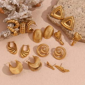 Close-up of assorted 18K gold plated vintage earrings on a textured stone surface