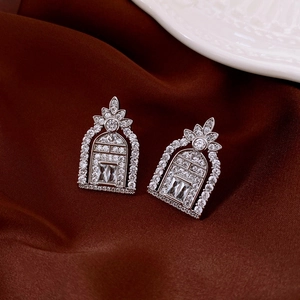 Macro shot of silver arch earrings with cubic zirconia on deep red satin background