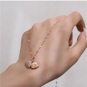 Close-up of a rose gold shell pendant necklace with micro-diamonds and a white pearl detail