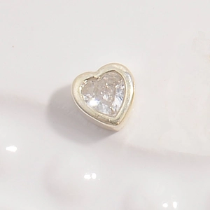 Macro detail of silver heart charm with sparkling heart-shaped zircon for DIY jewelry