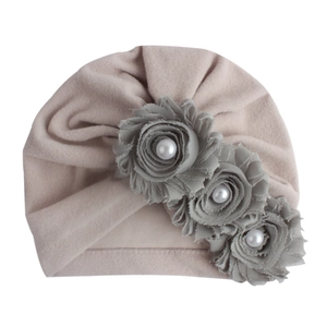 Detail der Baby-Turbanmütze mit grauen Stoffblumen und eleganten Perlenmitten