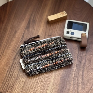 Close-up of woven fabric coin purse with textured yarn detail and zipper puller