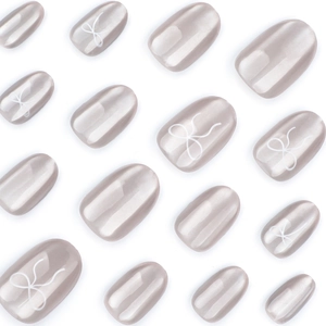 Faux ongles œil-de-chat champagne avec motifs nœuds blancs et finition nacrée élégante