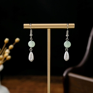 Close-up of light green beads and drop pearl tassels on Chinese style floral earrings