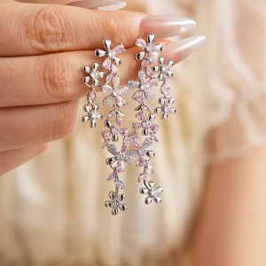 Detail of silver flower tassel earrings with pink and clear crystals worn by a model