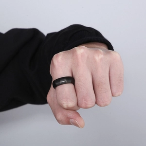 Macro shot of a minimalist matte black titanium ring for men shown on finger