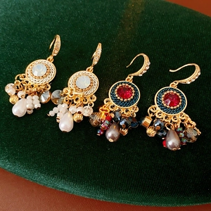 Detailaufnahme von Vintage Goldohrringen mit Perlen und Strass auf grünem Samt