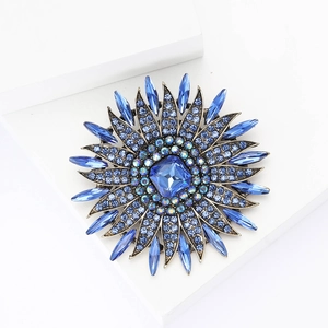 Detailed macro view of luxurious sunflower brooch with blue gemstone on white pedestal